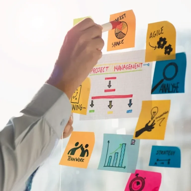 Main visible hand placing colorful post-it notes on une surface vitrée avec des illustrations variées.
