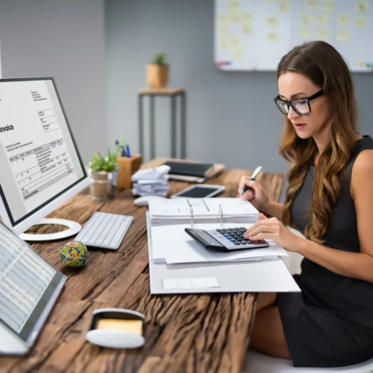 Femme travaillant à un bureau moderne avec un ordinateur et une calculatrice.