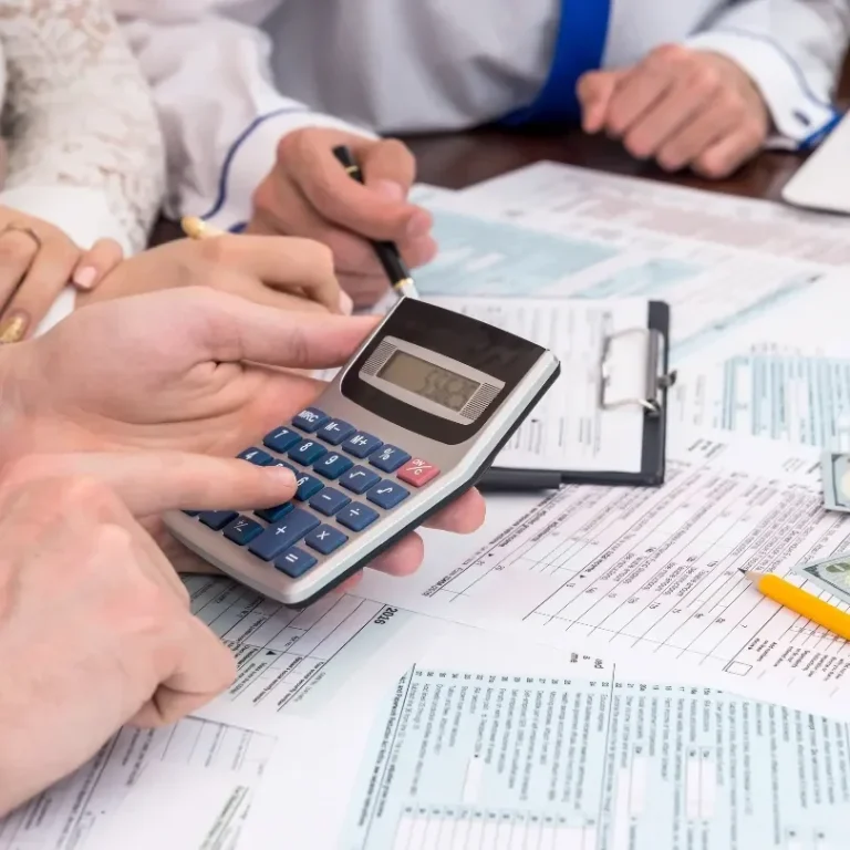 Des mains utilisant une calculatrice parmi des documents et des notes financières.