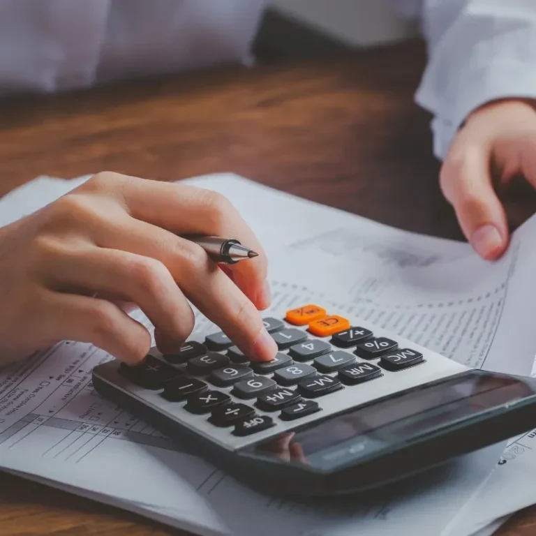 Une main utilisant une calculatrice sur une feuille de papier.