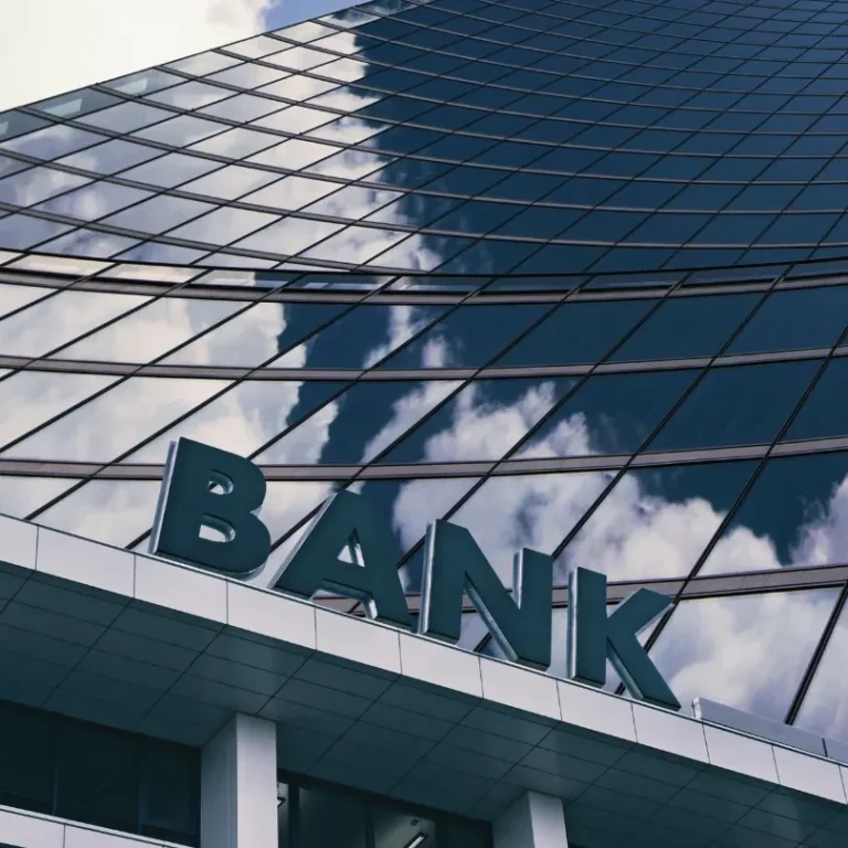 Façade en verre d'un immeuble avec le mot "BANK" en grandes lettres.